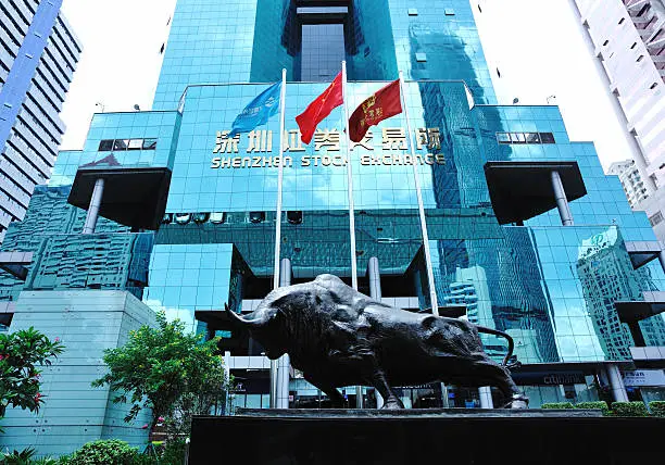 "Shenzhen city,China - July 11,2012: The bull sculpture and flags in front of the Building of Shenzhen Stock Exchange,Guangdong province,China"